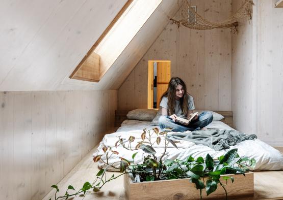 a woman sitting on a bed in a attic