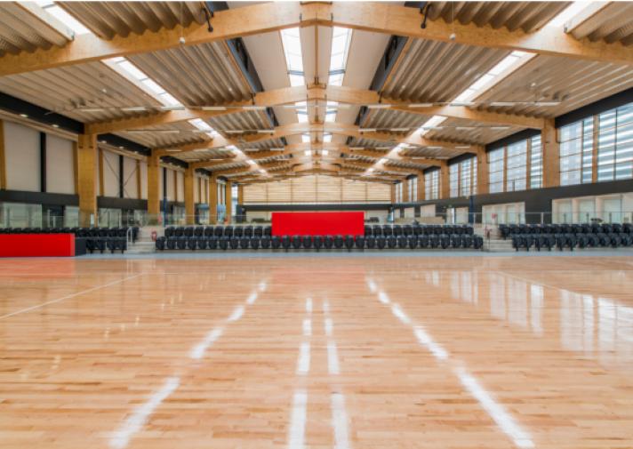 a large indoor gym with wooden floor and chairs