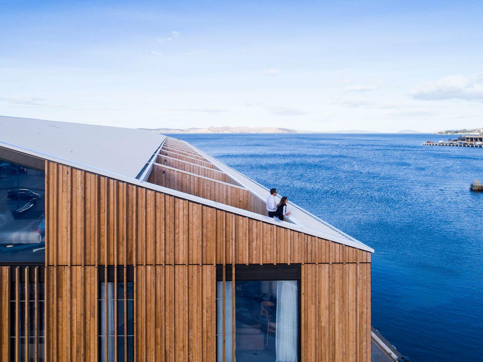 a couple sitting on a roof overlooking a body of water