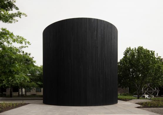 a black cylindrical structure with trees in the background