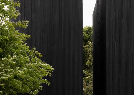 a tall black building with trees in the background