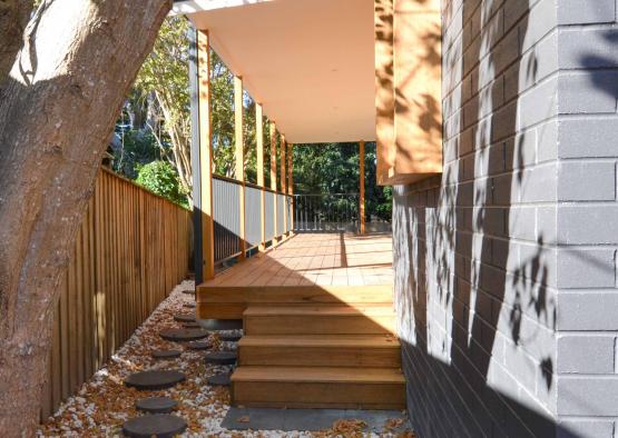 a porch with a stone walkway and a tree