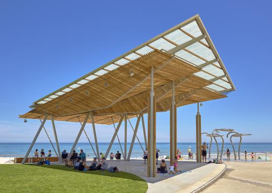 a beach covered area with people sitting on grass and a swing
