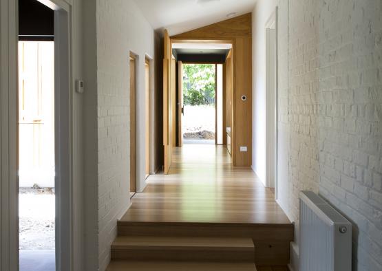 a hallway with wood stairs and a white brick wall