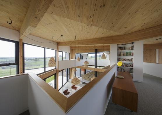 a room with a wood ceiling and a table and bookshelf