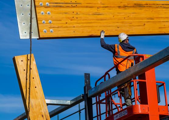 a man in a safety helmet on a platform holding a wood beam