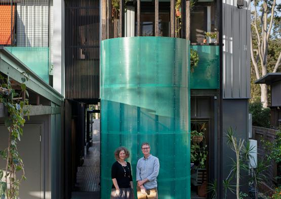 a man and woman standing in front of a green cylindrical structure