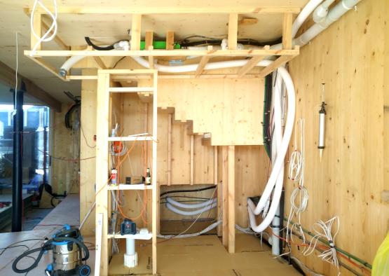 a room with a wood wall and a ladder and white pipes
