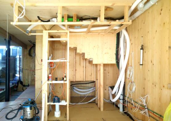 a room with a wood wall and a ladder and white pipes