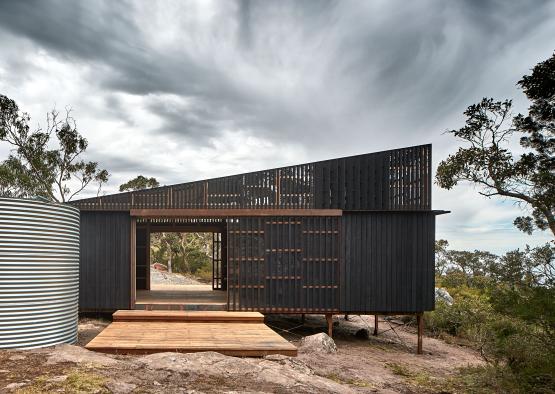 a black building with a wooden deck and a wood porch