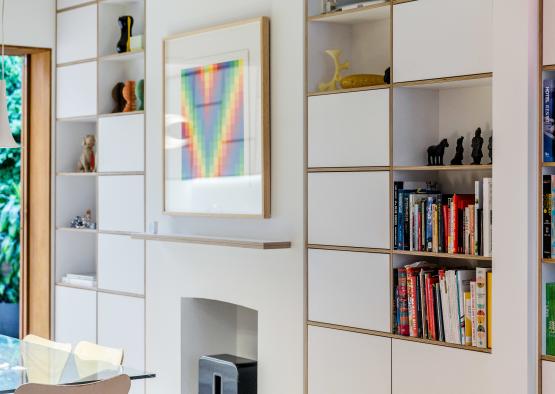 a white shelves with books and a picture on the wall