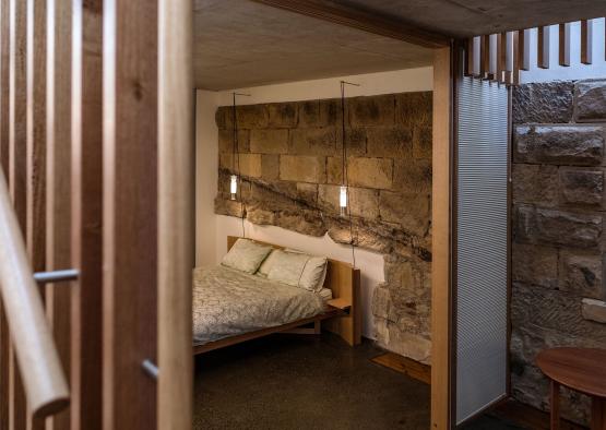a bed with pillows and lights from a stone wall