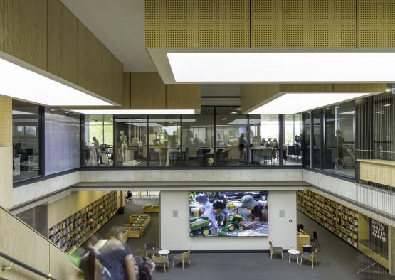 a large room with a large screen in the middle of the library