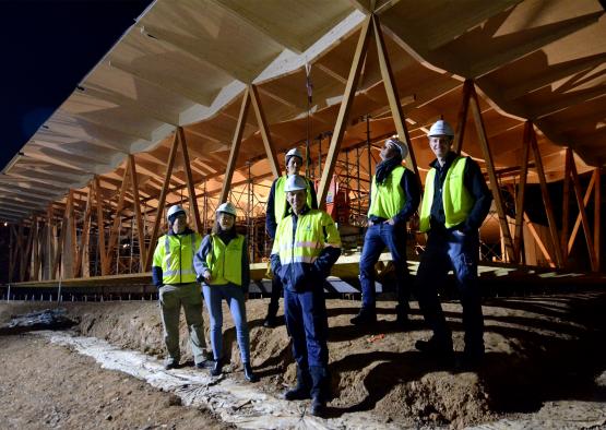 a group of people in safety vests and helmets standing in dirt