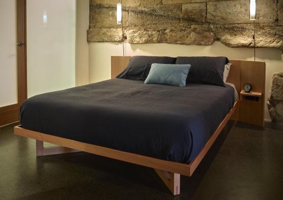 a bed with a stone wall behind it