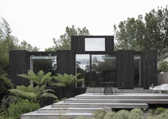 a black house with a wooden deck and stairs