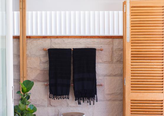 a towel rack with black towels on a brick wall
