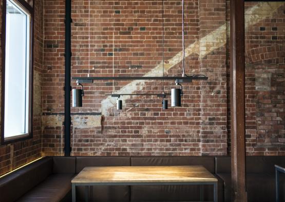 a table and a bench in a room with a brick wall