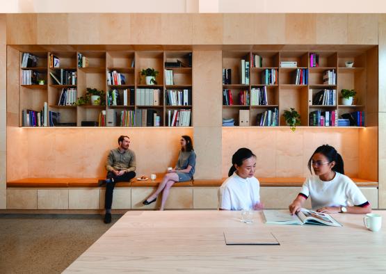 people sitting at a table with books on the wall