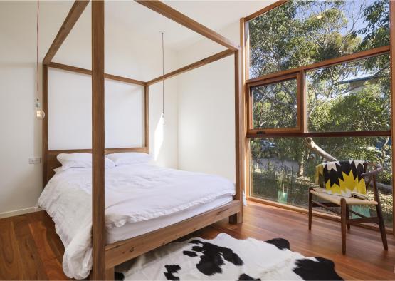 a bed with a white sheet and a black and white rug in front of a window