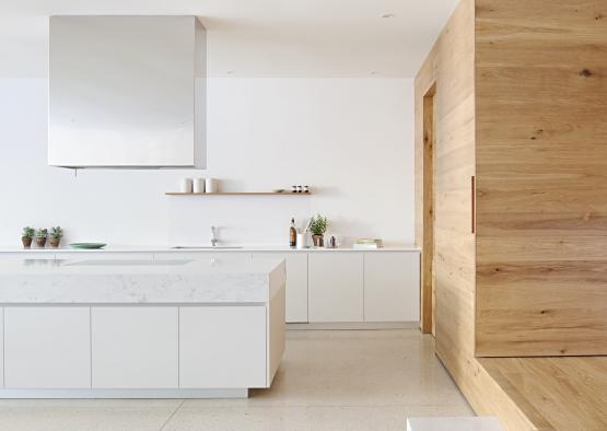a white kitchen with a wood wall and a white countertop