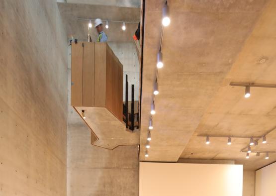 a man in a helmet standing on a platform in a room with a staircase