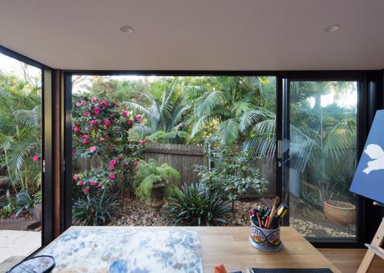 a desk with a cup on it and a glass door with a garden outside