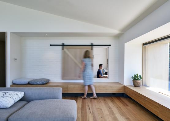 a woman walking in a room with a man in the background