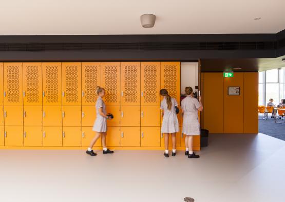 a group of girls in school uniforms standing in front of yellow lockers