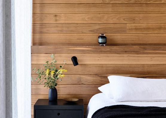 a bed with a black nightstand next to a wood paneled wall