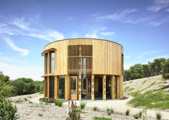 a circular building with a grassy hill and trees