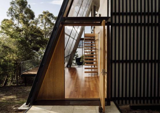 a triangular building with a wooden door and stairs