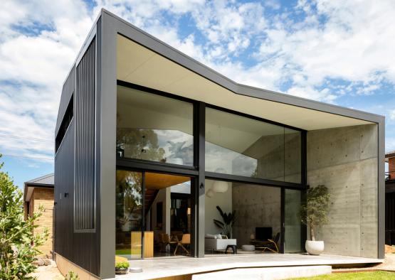 a house with a concrete wall and glass walls