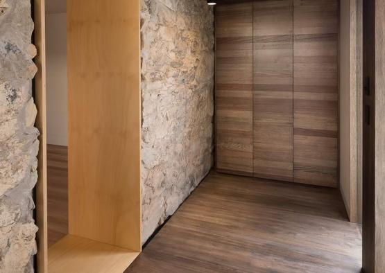 a hallway with a door and a stone wall