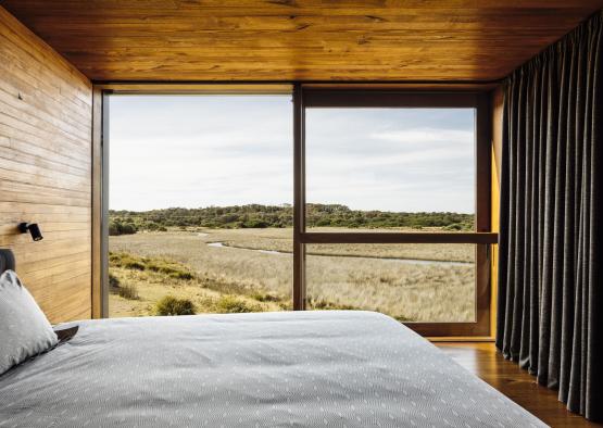 a bed with a view of a field and a river through a window