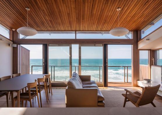 a living room with a table and chairs and a view of the ocean