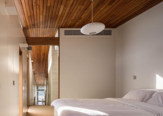 a bedroom with a wood ceiling and a white bed