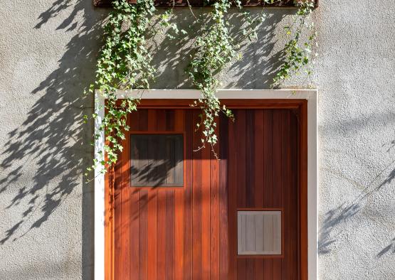a door with a window and a planter on the side of a building