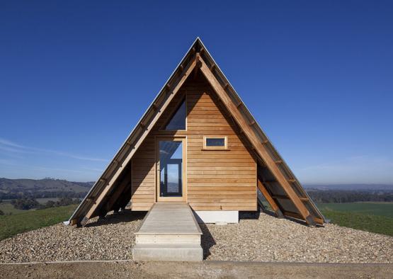 a triangular wooden house with a triangular roof