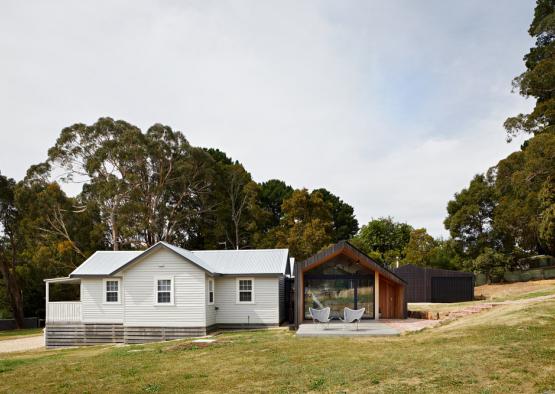 a house with a glass wall and a building with trees in the background