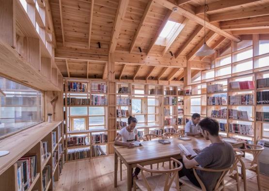 a group of people sitting at a table in a room with bookshelves