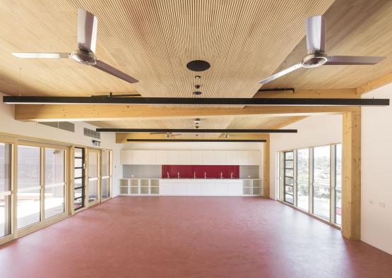 a large room with red floor and ceiling fans