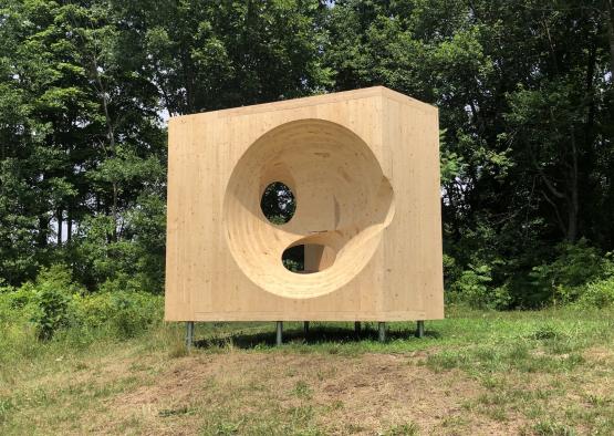 a wooden square sculpture in a grassy area