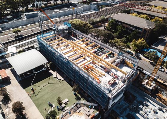 a building under construction with a crane and trees