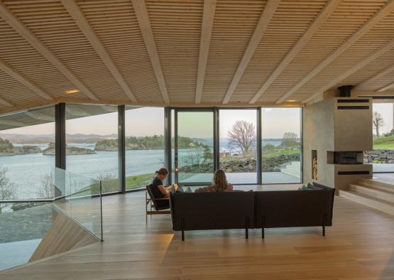 a couple of people sitting on a couch in a room with a view of water