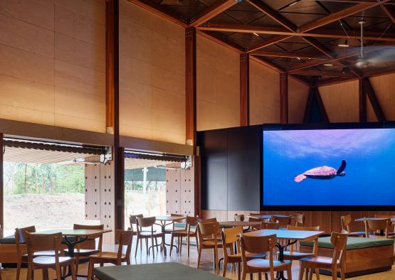 a room with tables and chairs and a large screen