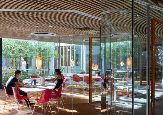 a group of people sitting at tables in a room with glass walls