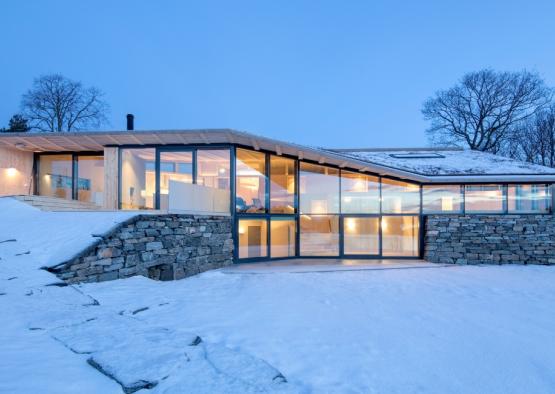 a house with a large glass wall and a stone wall
