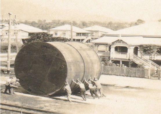 a group of men pushing a large cylinder