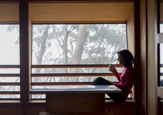 a woman sitting on a window sill with a cup of coffee